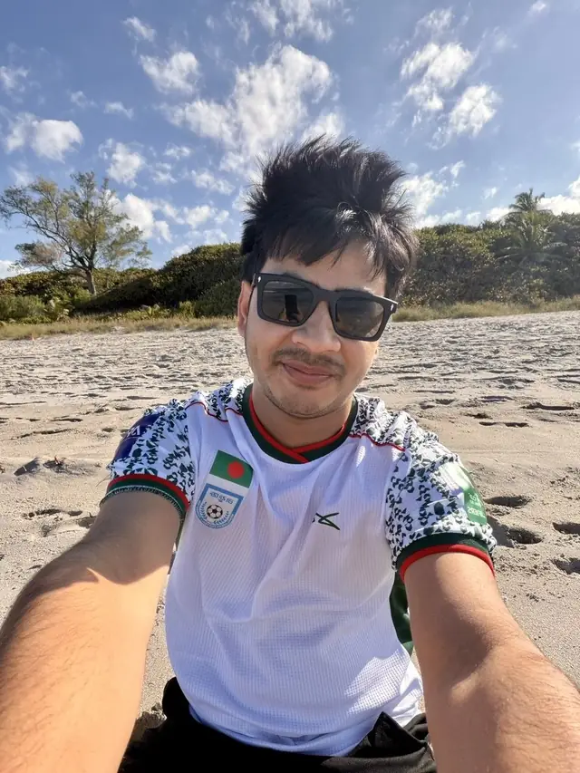 Naim Bin Hasan wearing the Bangladesh football jersey on the beach.